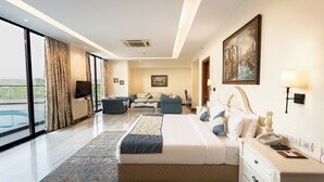 A modern hotel room with a large bed, a desk, a chair, a sofa, and a view of the city. - The BellaVista Hotel Chandigarh Panchkula (Panchkula)