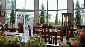 A restaurant with large windows, wooden tables, and chairs. - The BellaVista Hotel Chandigarh Panchkula (Panchkula)