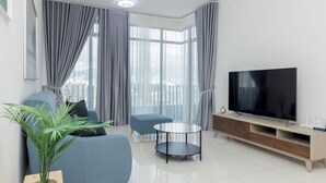 Ein modernes Wohnzimmer mit einer Couch, einem Couchtisch, einem Fernseher und einer Pflanze.