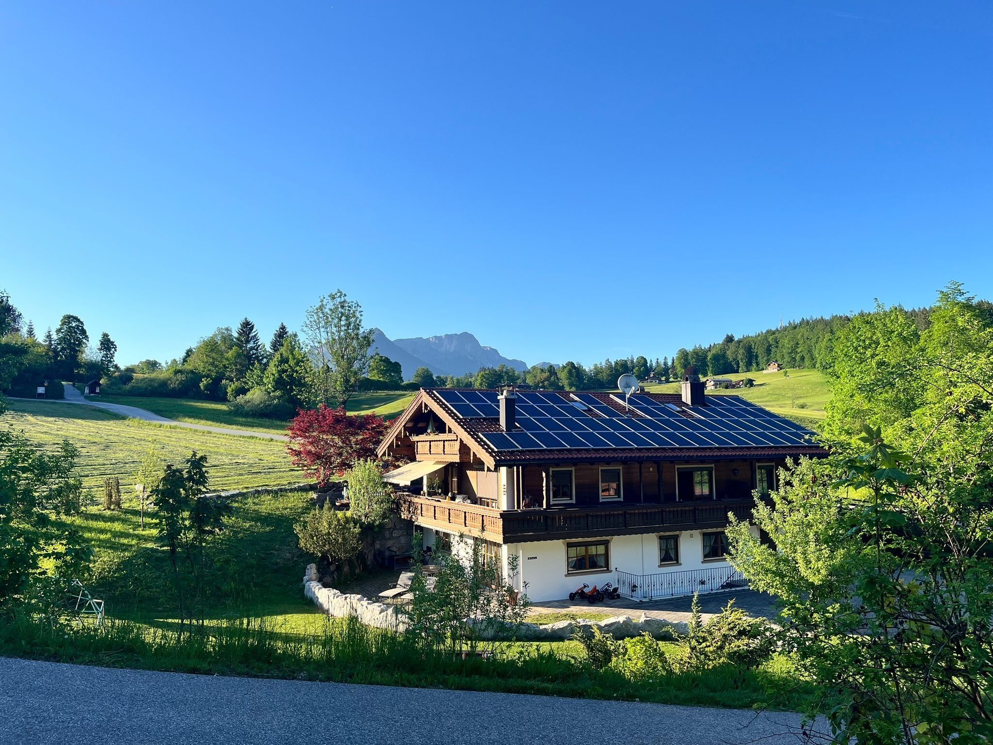 Ein Chalet mit geneigtem Dach, Solaranlagen und einem Steinfundament.