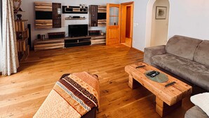 Un salon spacieux doté d’un plancher en bois, d’un canapé, d’une table basse et d’un téléviseur.