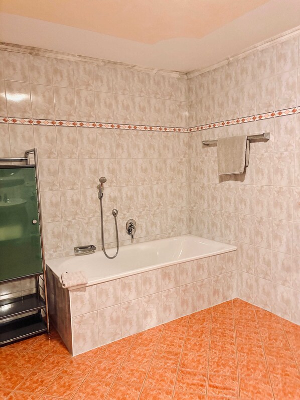 Un baño con bañera, ducha y toallero.