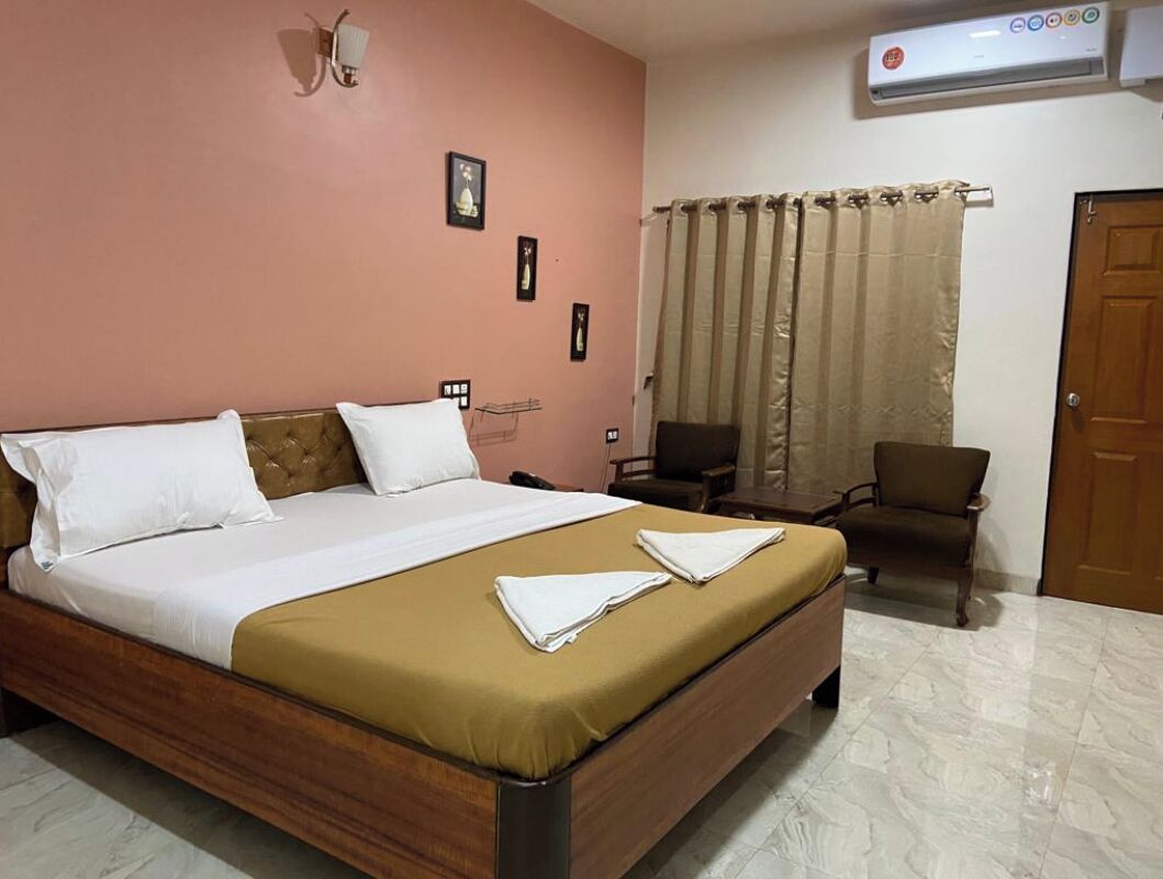 Una habitación de hotel con una cama, una silla, un escritorio y una cortina.