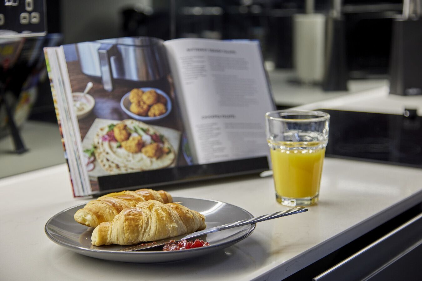 A breakfast setting with a croissant on a plate, a glass of orange juice, and a menu.