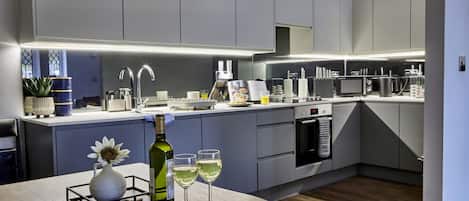 A modern kitchen with grey cabinets, a built-in oven, and a stainless steel range hood.