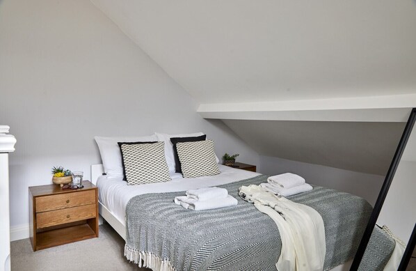 A bedroom with a bed, bedside tables, a nightstand, and a mirror.