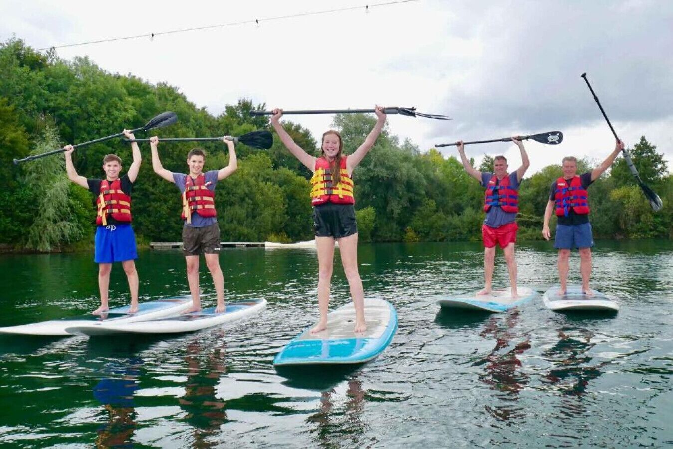 Five people on paddleboards in a body of water, each holding a paddle.