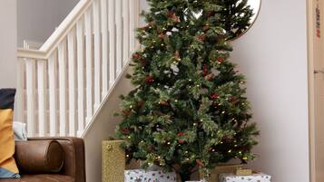 A living room with a Christmas tree, a staircase, and a toy train set.