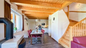 Eine moderne Küche mit Holzbalken, einem Essbereich mit roten Stühlen und einer Treppe.