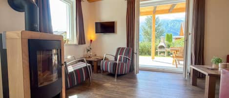 A cozy room with a fireplace, a TV, a dining table, and a view of the outdoors.