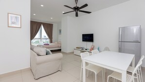 A modern living room with a white sofa, a dining table with chairs, a ceiling fan, a TV, and a refrigerator. - Mansion One, by BAYAN (George Town)