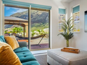 Un salon avec un canapé, une petite table et une vue sur un paysage montagneux, visible à travers de grandes fenêtres.