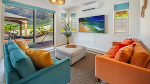 A modern living room with a large window, a sofa, a coffee table, and a TV.