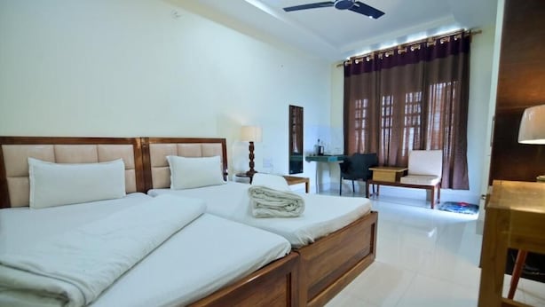 Ein Hotelzimmer mit Doppelbett, Schreibtisch, Stuhl und Deckenventilator.