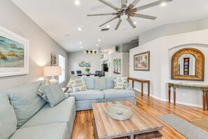 Un salon moderne avec un canapé bleu clair, une table basse en bois et un ventilateur de plafond.