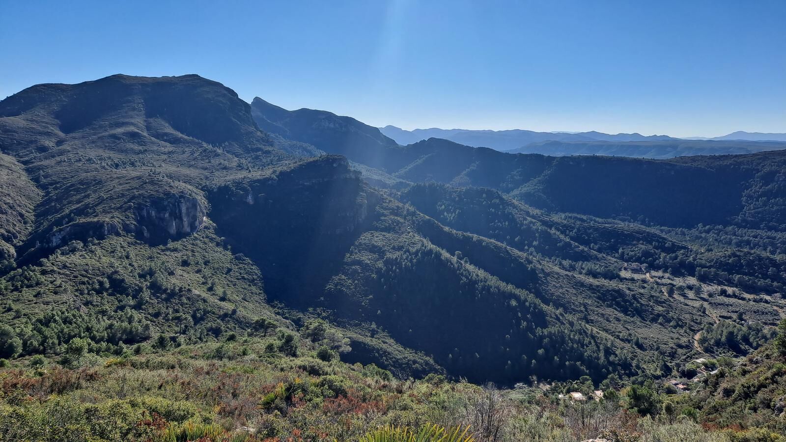 Un paisaje montañoso con vegetación densa y cielo despejado.