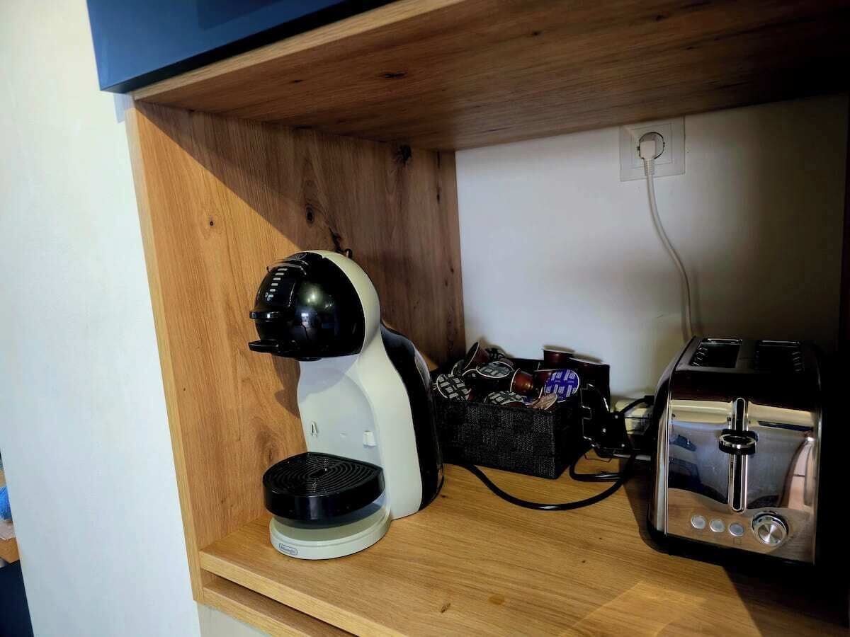 Une petite cuisine équip ée d’une machine à café, d’un grille-pain et d’un panier rempli d’en-cas.
