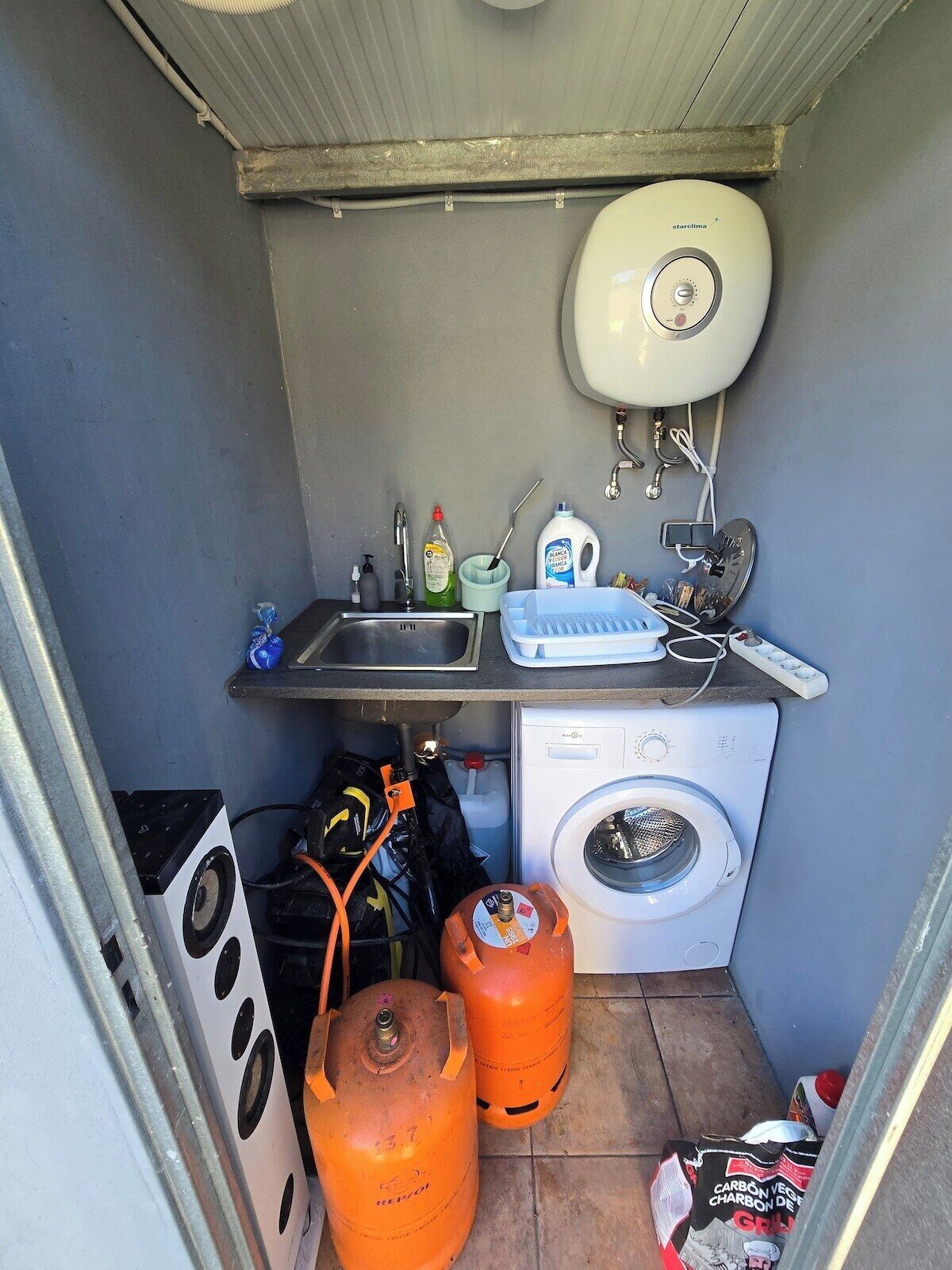 Une petite cuisine équipée d’un évier, d’une cuisinière et d’un lave-linge.