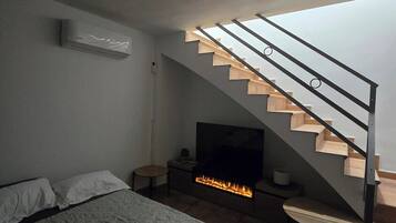 Ein modernes Schlafzimmer mit einem Bett, einem Fernseher, einem Kamin und einer Treppe.