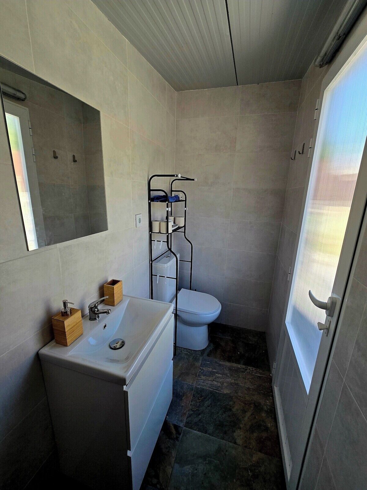 Un baño pequeño con lavamanos blanco, inodoro y cabina de ducha.