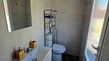 Un baño pequeño con lavamanos blanco, inodoro y cabina de ducha.