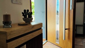 Une console en bois ornée d’une bougie et d’une plante en pot, une porte-fenêtre coulissante et une vue sur l’extérieur.
