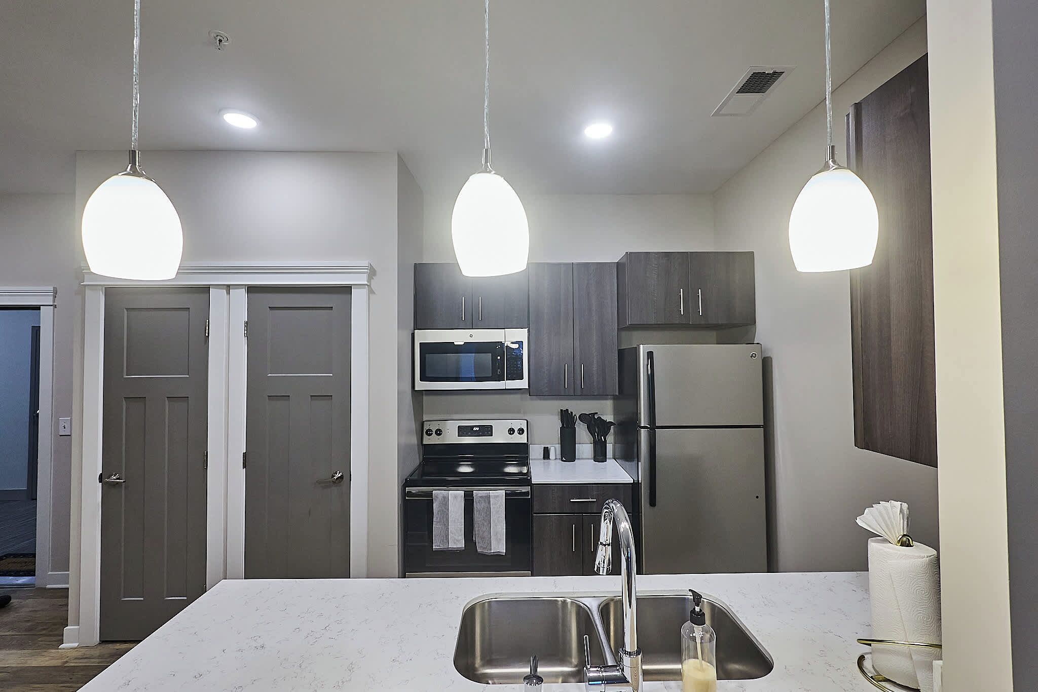 Una cucina moderna con isola centrale, elettrodomestici in acciaio inossidabile e illuminazione a sospensione.