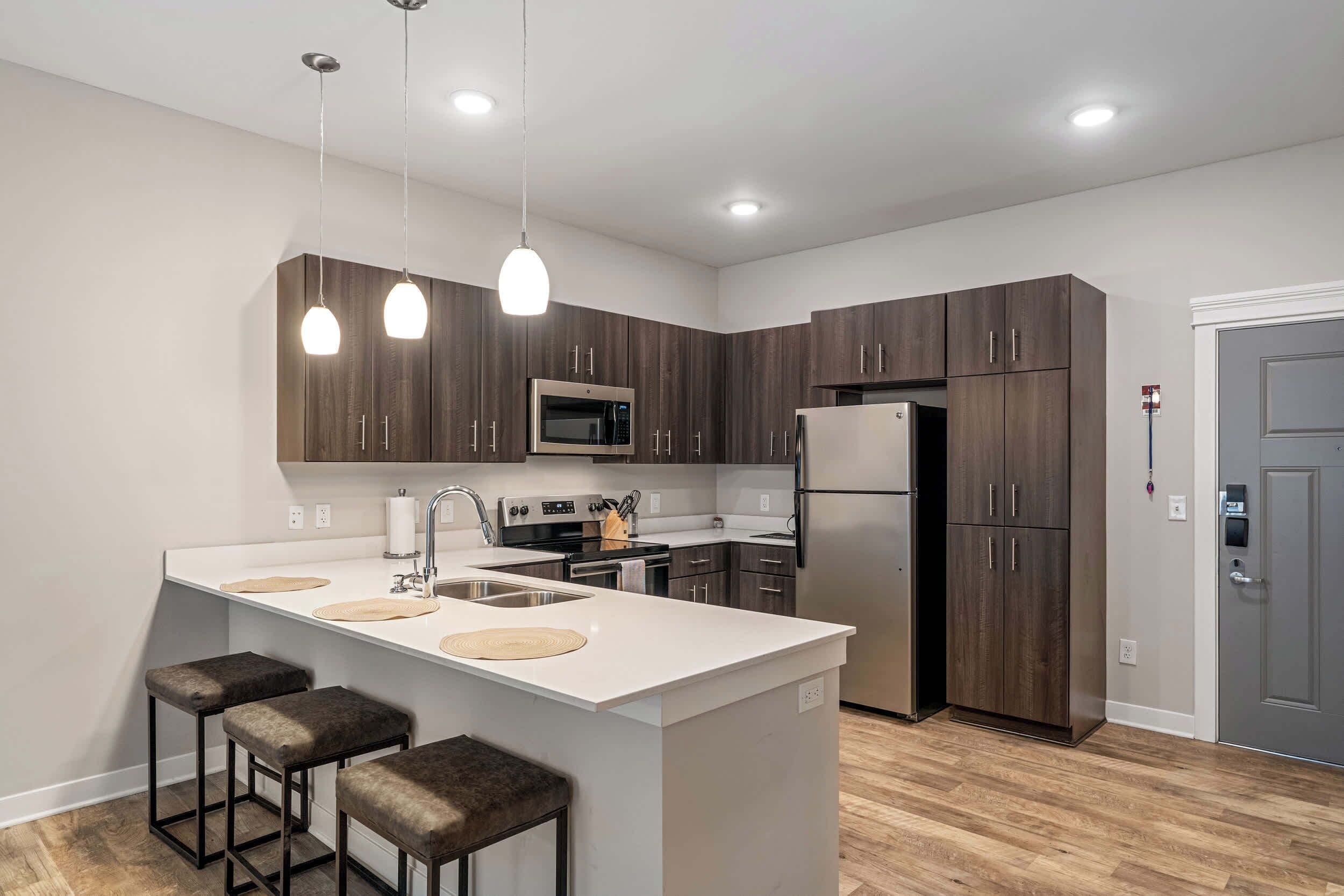 A modern kitchen with a central island, stainless steel appliances, and dark wood cabinets.