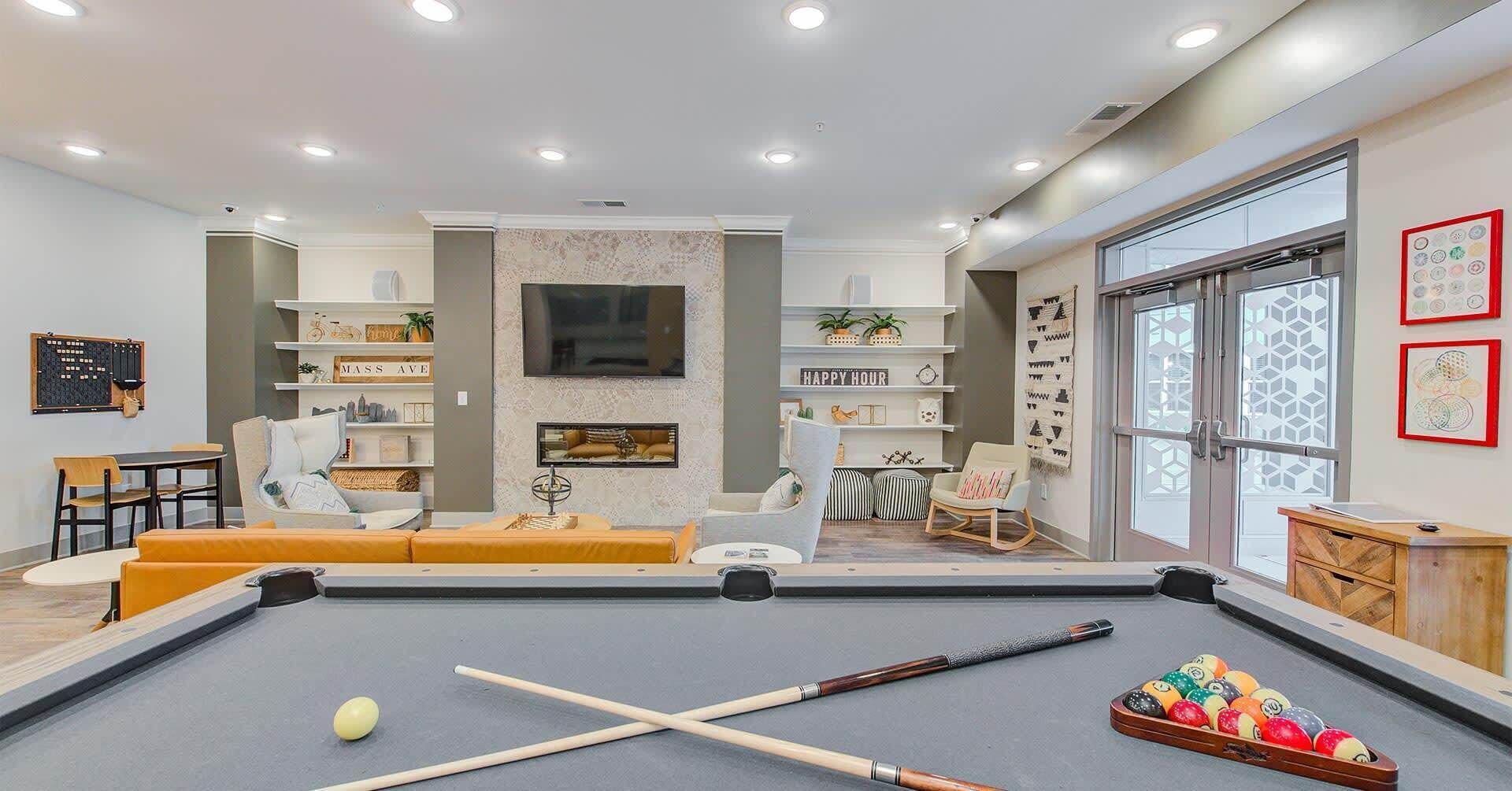 A modern living room with a pool table, comfortable seating, and a large TV.