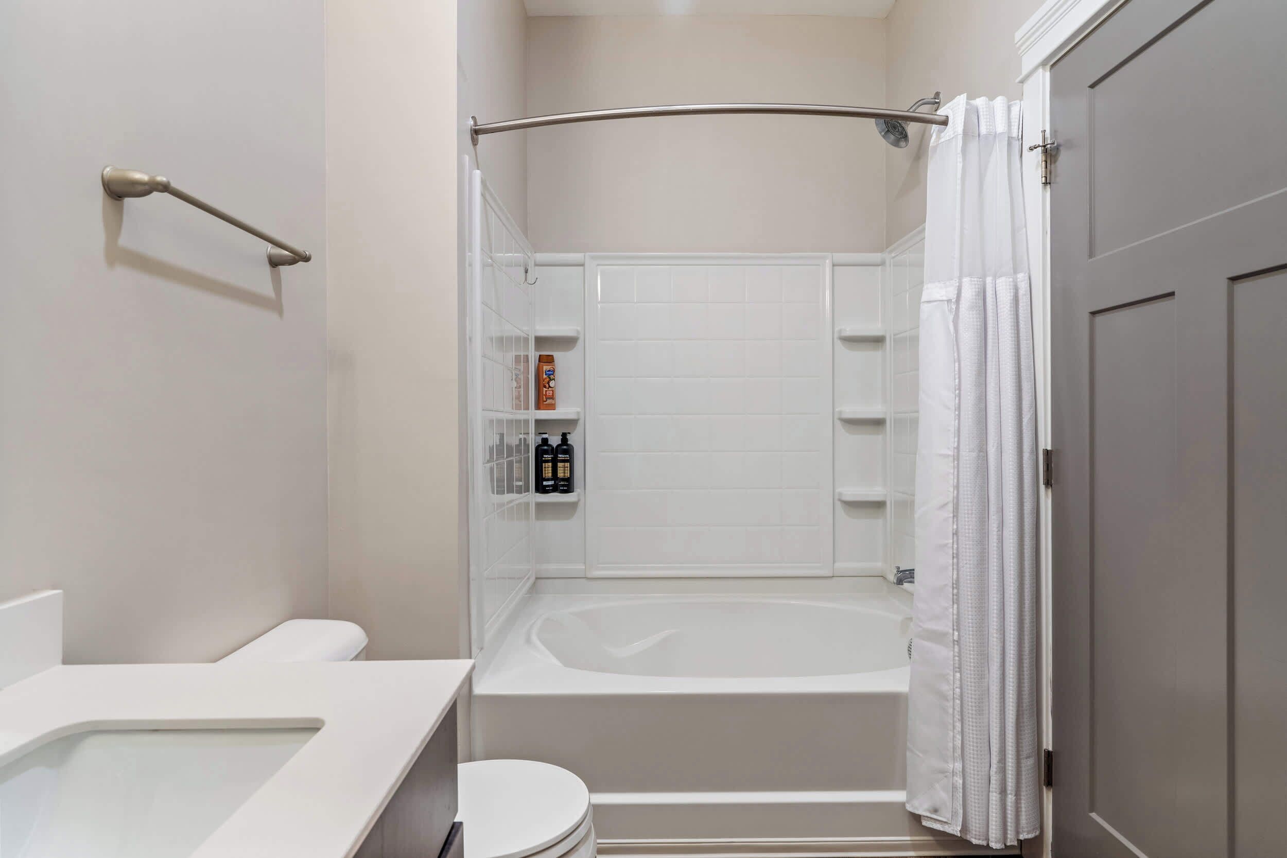 A modern bathroom with a bathtub, toilet, and a shower area.