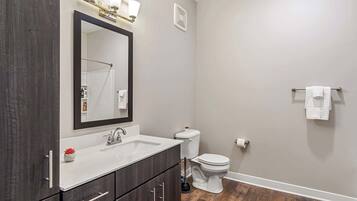 A modern bathroom with a dark wood vanity, white sink, and a large mirror.