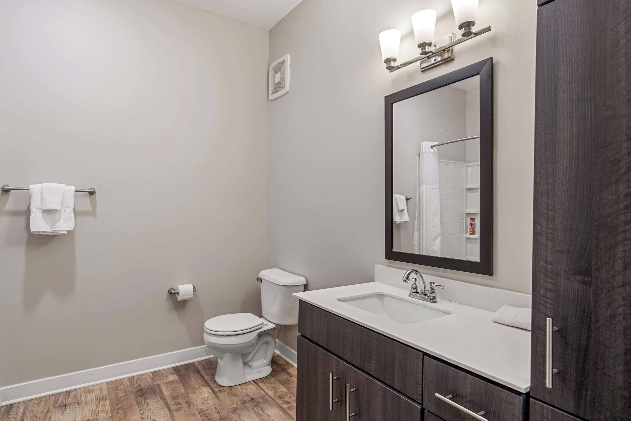 A modern bathroom with a toilet, sink, and mirror.
