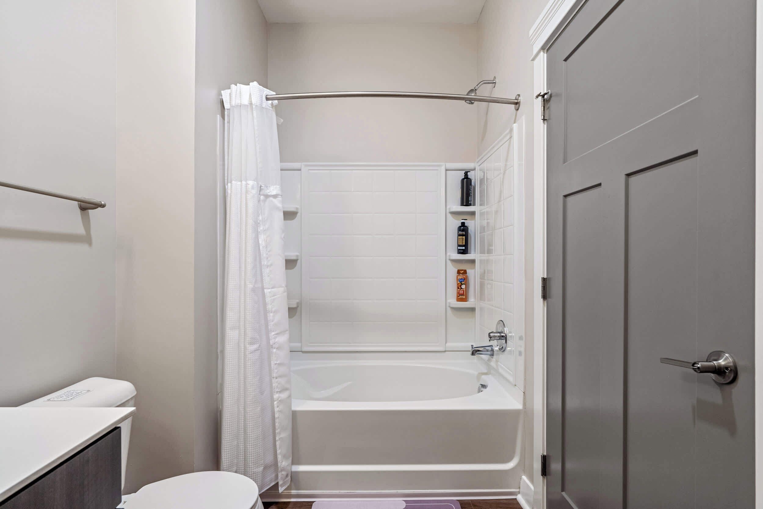 A bathroom with a bathtub, toilet, and a shower curtain.