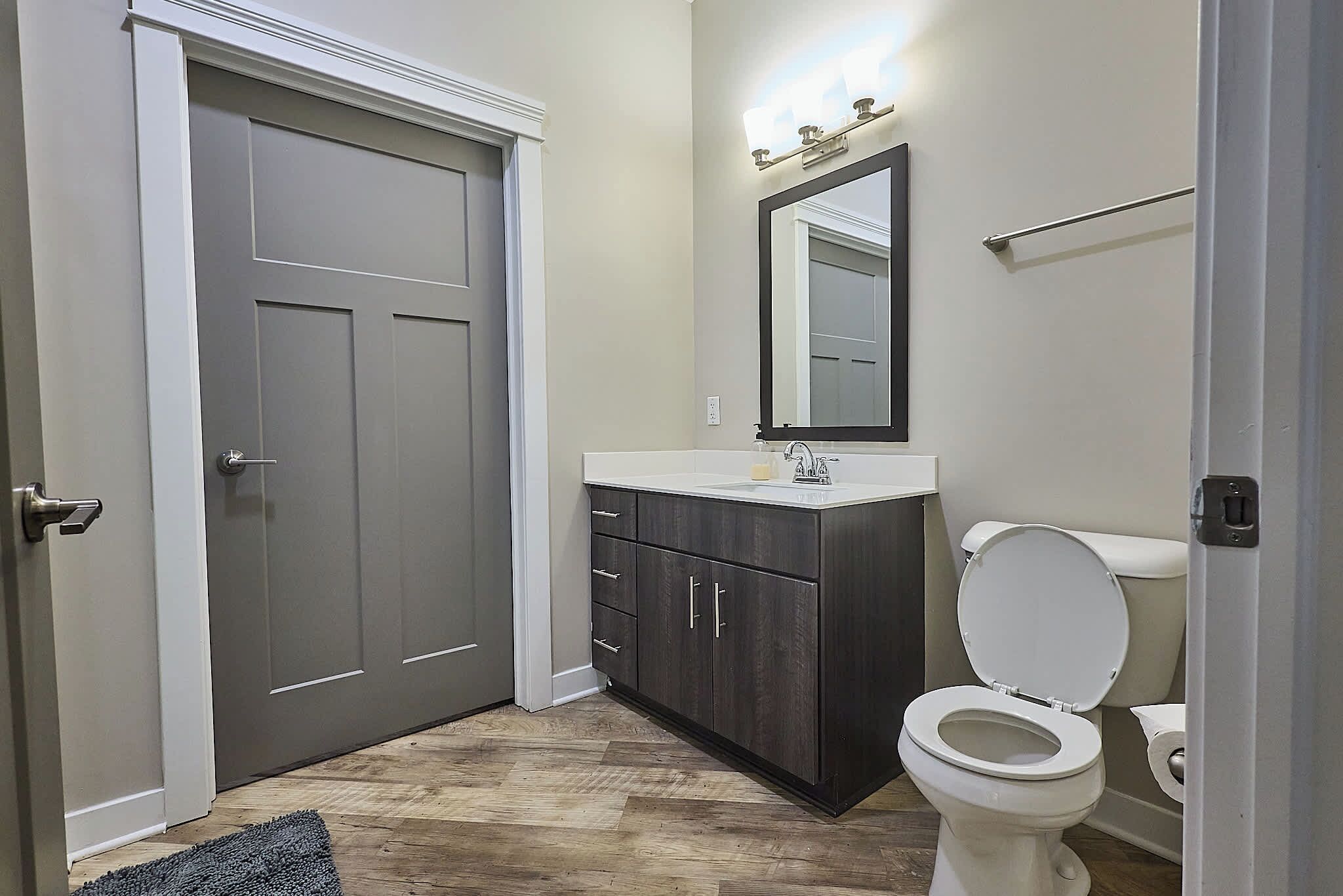 A bathroom with a toilet, vanity, and a large mirror.