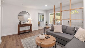 A modern living room with a grey sofa, wooden coffee table, and a console table with a lamp.