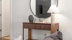 A modern console table with a round mirror, a vase, and books.