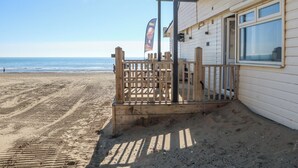 A beachfront property with a wooden deck and a window overlooking the ocean.