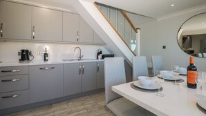 A modern kitchen with grey cabinets, a built-in oven, and a dining area with a table set for two.