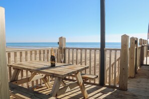 Una terraza de madera con mesa y sillas, con vistas a la playa.