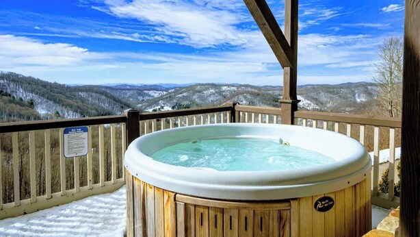 A hot tub on a wooden deck with a view of snowy mountains. - 5 Min to Hatley Pointe~Hot Tub~Games~Dog Friendly (Mars Hill)