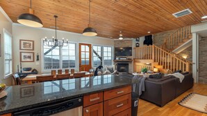 A spacious kitchen with a large island, wooden ceiling, and a stone fireplace. - 5 Min to Hatley Pointe~Hot Tub~Games~Dog Friendly (Mars Hill)