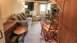 A cozy living room with a sofa, chairs, a small table, and a fireplace. - Old Cottage (Ulverston)