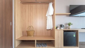 Un baño moderno con tocador de madera, refrigerador negro, televisor y zona de ducha.