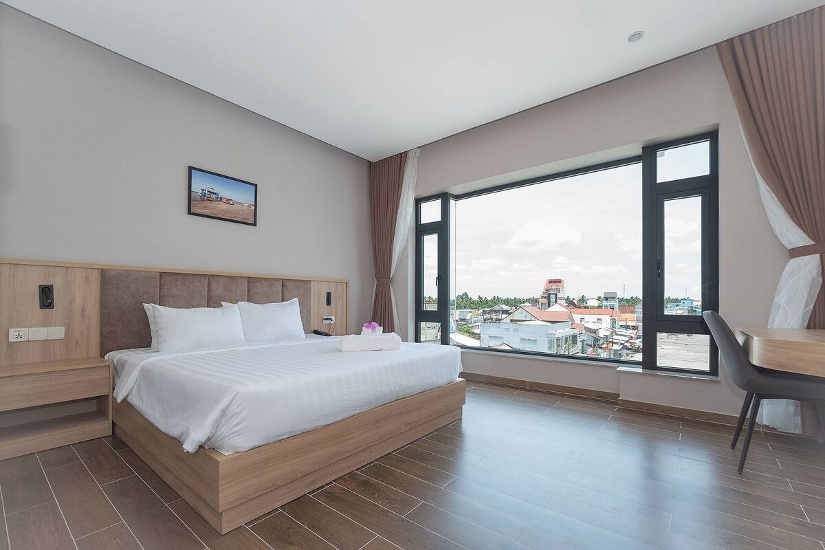 Una camera d'albergo moderna con un letto grande, una scrivania e una finestra con vista sulla città.