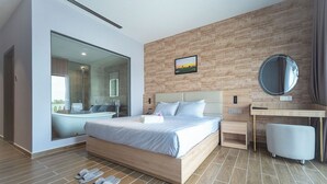 Una habitación de hotel moderna con una cama grande, un escritorio, un espejo y un baño con bañera y ducha.