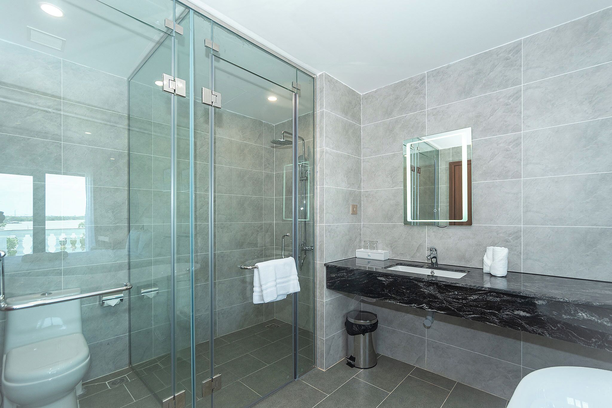 A modern bathroom with a glass-enclosed shower, a marble sink, and a large mirror.
