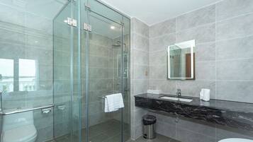 A modern bathroom with a glass-enclosed shower, a marble sink, and a large mirror.