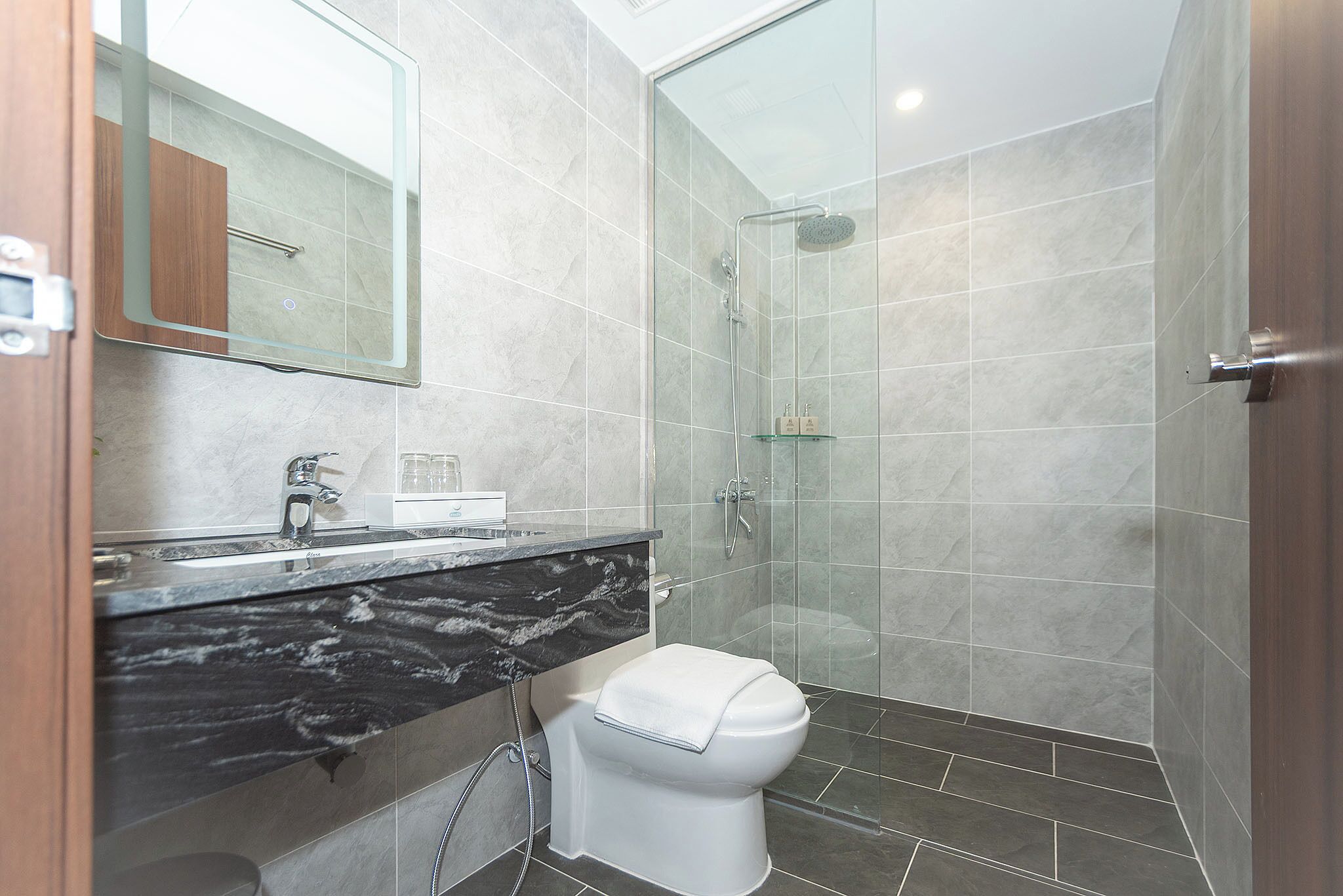 Ein modernes Badezimmer mit Waschtisch aus Marmor, Toilette und einer Duschkabine.