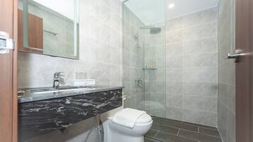 Ein modernes Badezimmer mit Waschtisch aus Marmor, Toilette und einer Duschkabine.