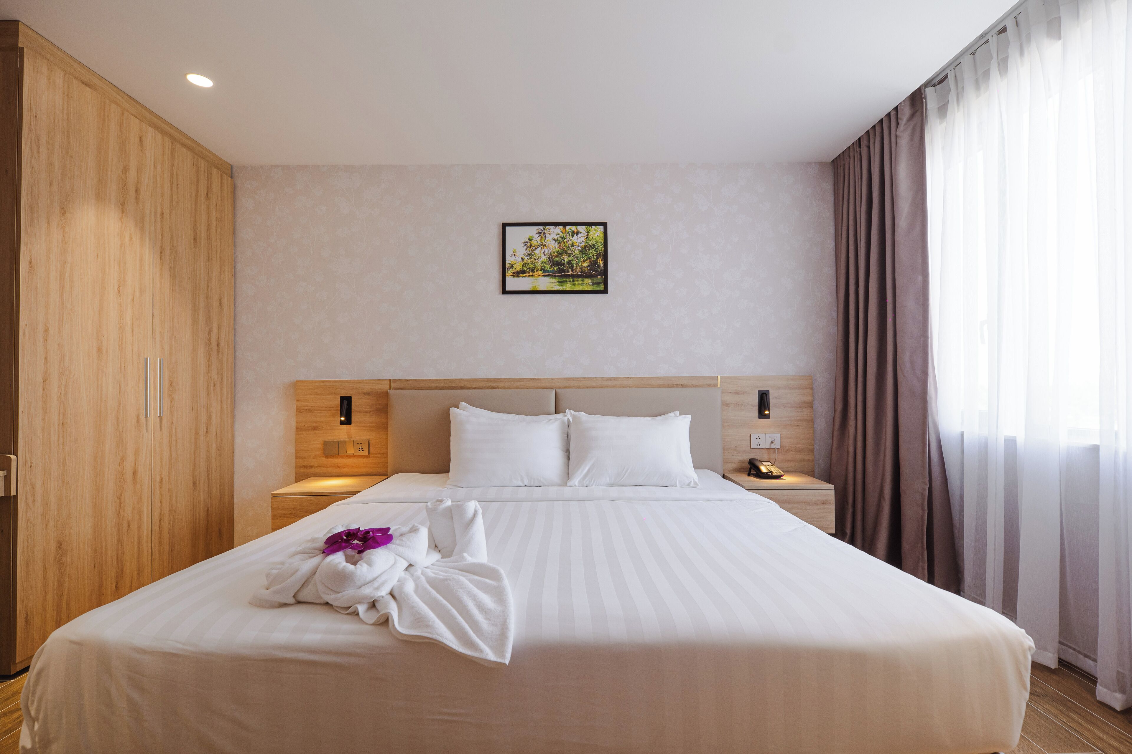 Ein Hotelzimmer mit einem großen Bett, einem Holzschrank und einem Nachttisch mit einer Lampe.